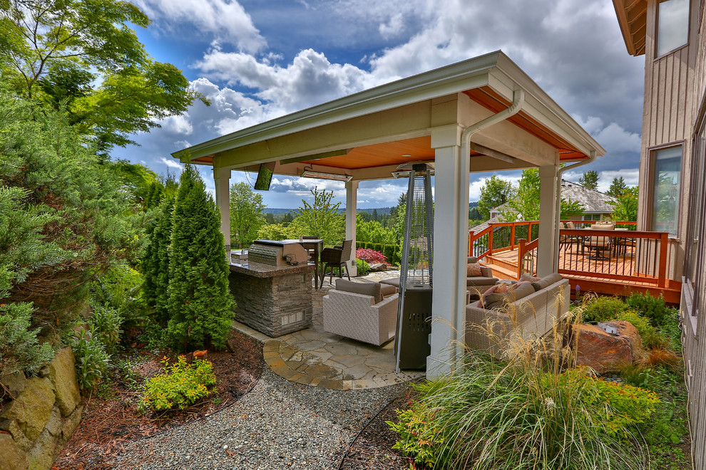 Modelo de patio clásico renovado grande en patio trasero con cocina exterior, adoquines de piedra natural y cenador