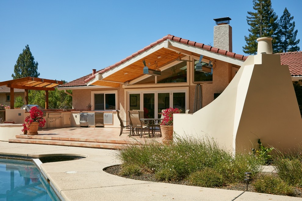 Esempio di un patio o portico american style di medie dimensioni e dietro casa con piastrelle e un tetto a sbalzo