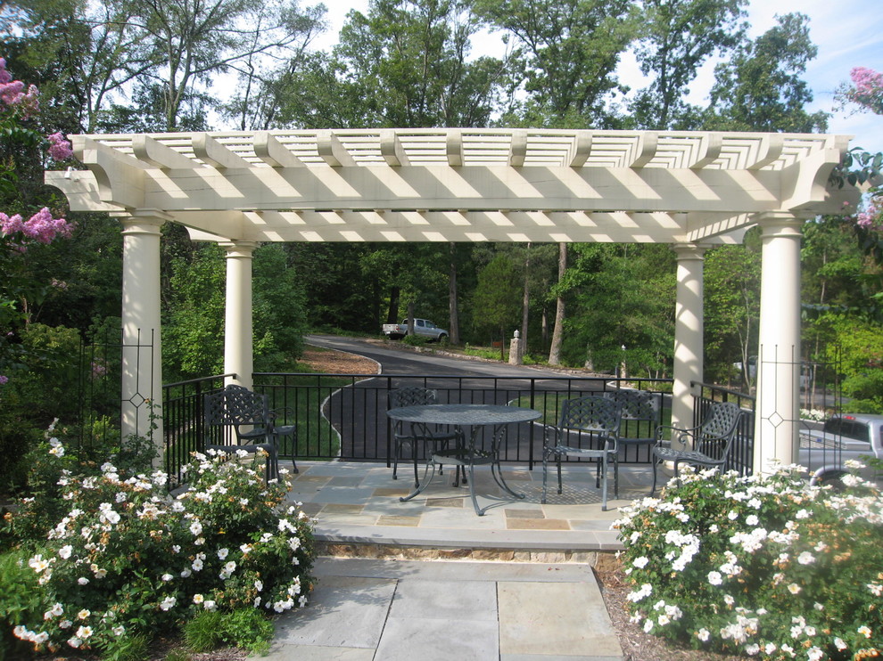 Idee per un ampio patio o portico classico davanti casa con pavimentazioni in pietra naturale e una pergola