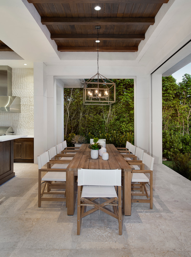 This is an example of a large patio in Miami with an outdoor kitchen, natural stone paving and a roof extension.