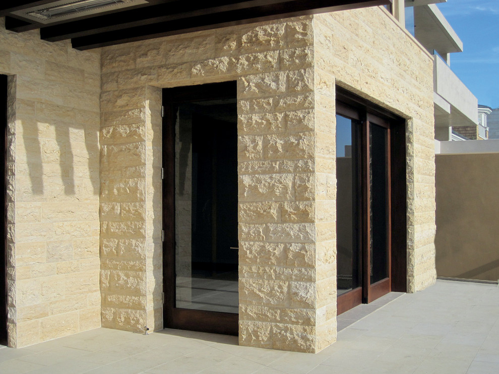 Idee per un patio o portico design di medie dimensioni e dietro casa con piastrelle e un tetto a sbalzo