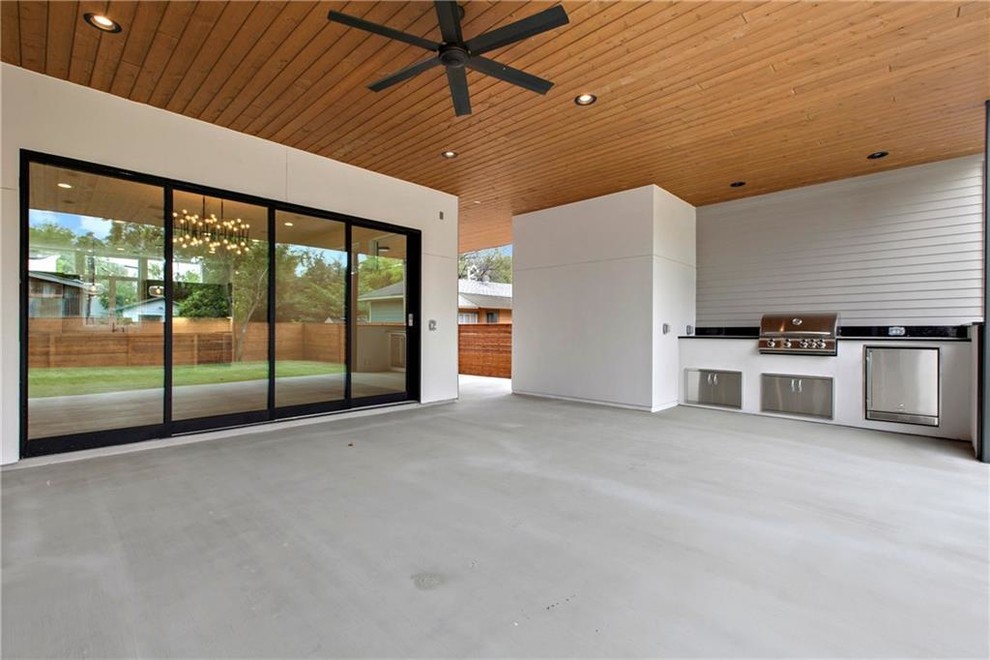 Cette image montre une terrasse arrière design de taille moyenne avec une cuisine d'été, des pavés en béton et une extension de toiture.