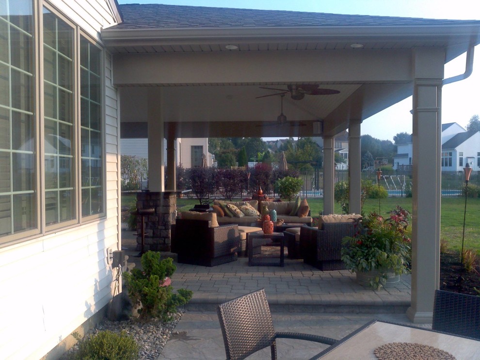 Foto di un grande patio o portico tradizionale dietro casa con un focolare, pavimentazioni in cemento e un tetto a sbalzo