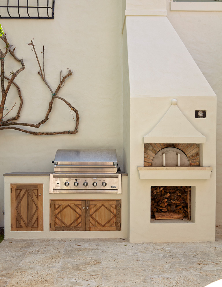 This is an example of a mediterranean back patio in Miami with an outdoor kitchen, tiled flooring and no cover.