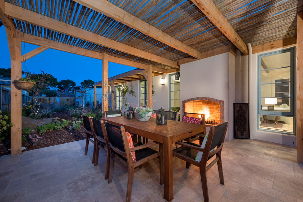Aménagement d'une grande terrasse arrière méditerranéenne avec un foyer extérieur, des pavés en pierre naturelle et une pergola.