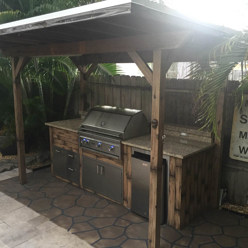 Example of an island style backyard patio kitchen design in Miami with a pergola