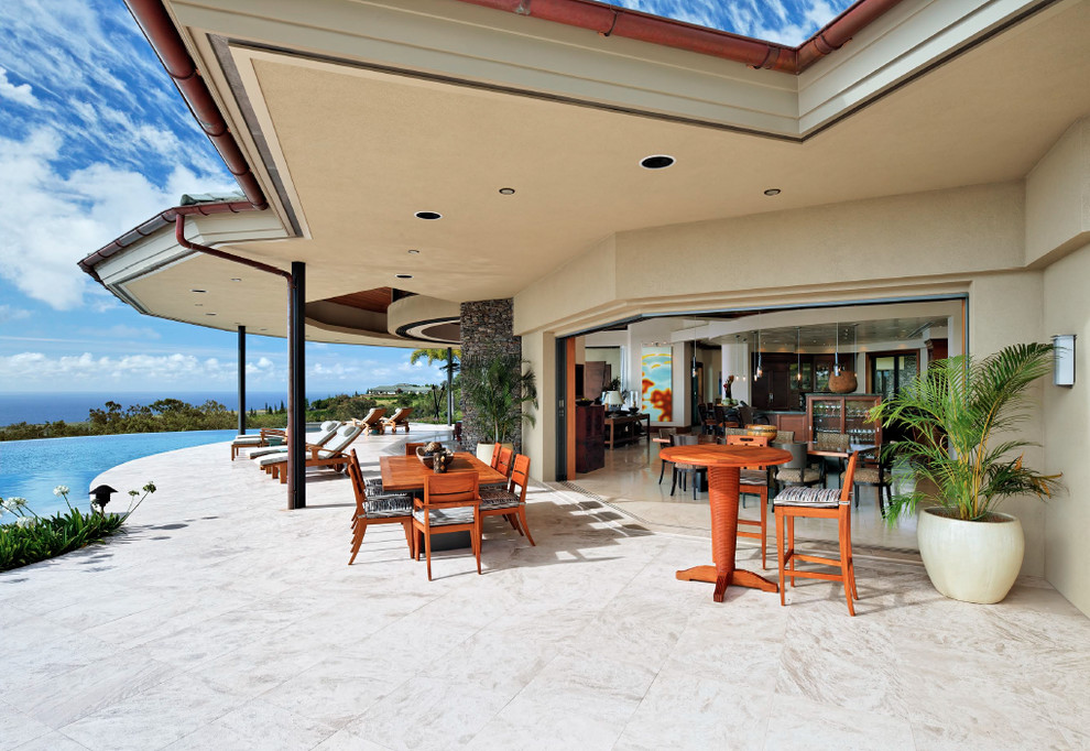 Inspiration for a large tropical backyard stone patio remodel in Hawaii with a roof extension