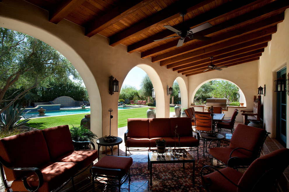 На фото: большой двор на заднем дворе в средиземноморском стиле с летней кухней, покрытием из плитки и навесом