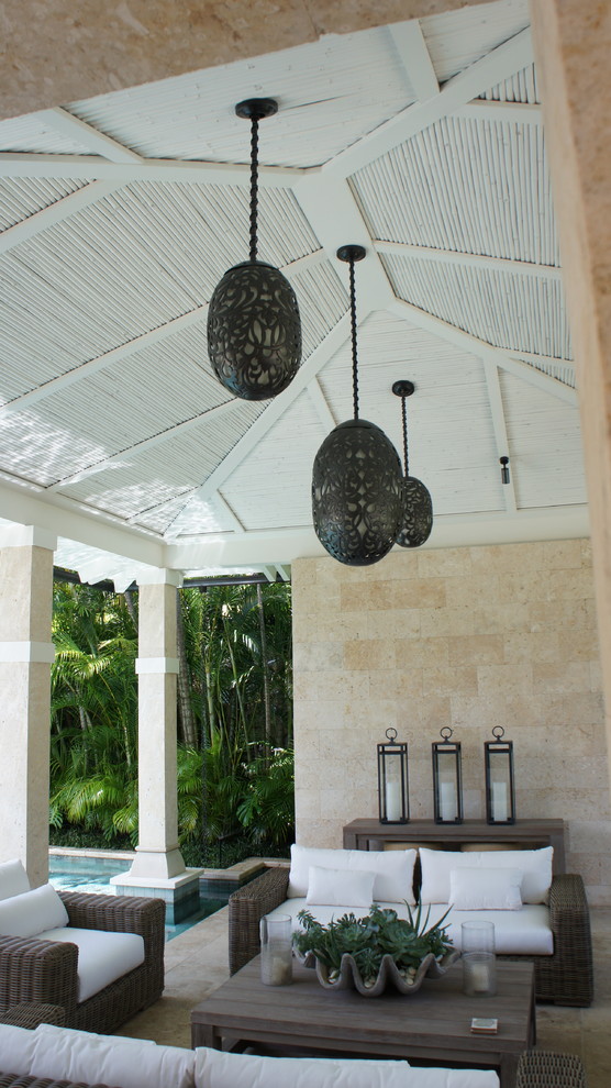 Idee per un ampio patio o portico tropicale dietro casa con piastrelle e un gazebo o capanno