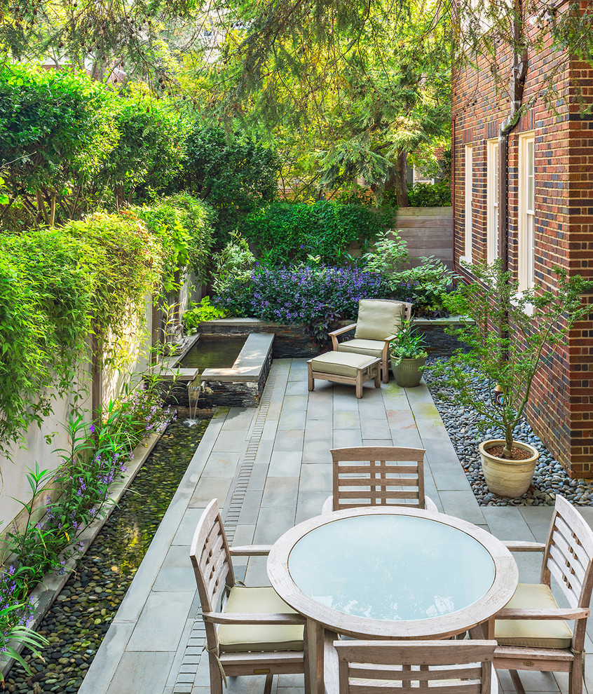 Design ideas for a small world-inspired back patio in DC Metro with a water feature, natural stone paving and no cover.