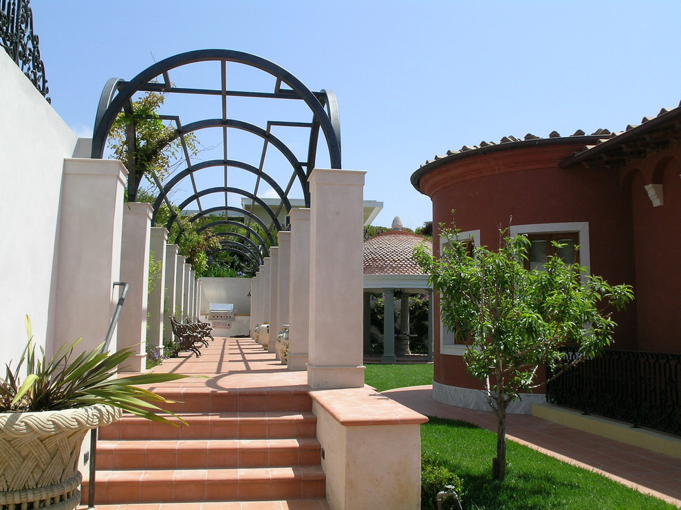 Example of a tuscan tile patio design in Orange County with a pergola
