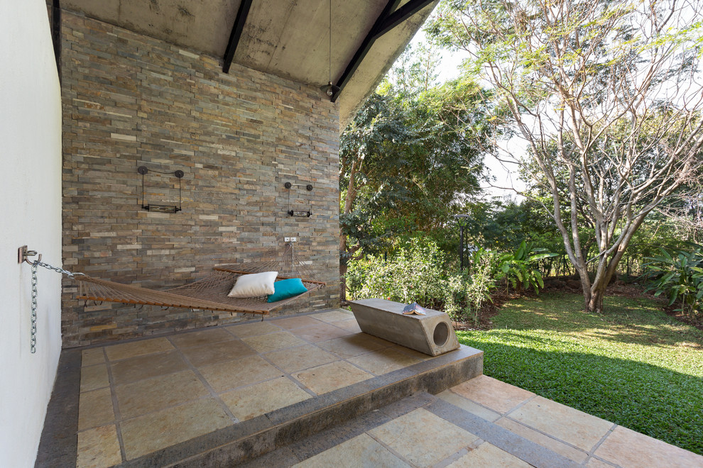 Стильный дизайн: двор на заднем дворе в современном стиле с покрытием из плитки и навесом - последний тренд