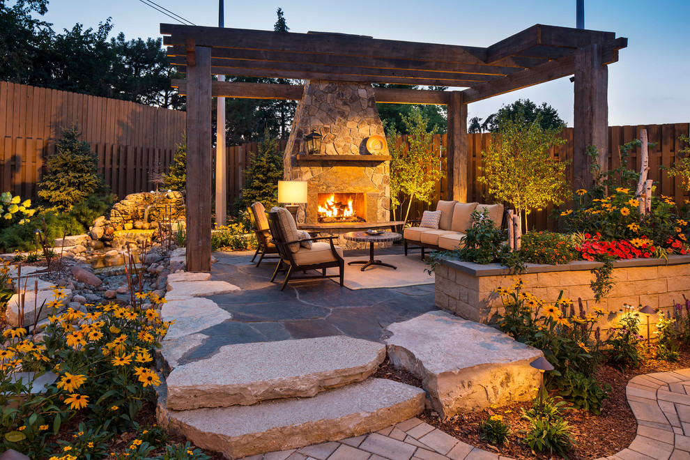 Medium sized traditional back patio in Minneapolis with a fire feature, natural stone paving and a pergola.