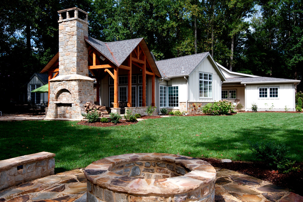 Idee per un grande patio o portico country dietro casa con un focolare, pavimentazioni in pietra naturale e un tetto a sbalzo