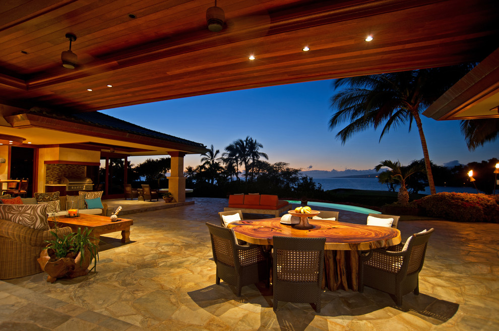Esempio di un patio o portico tropicale con pavimentazioni in pietra naturale e un tetto a sbalzo