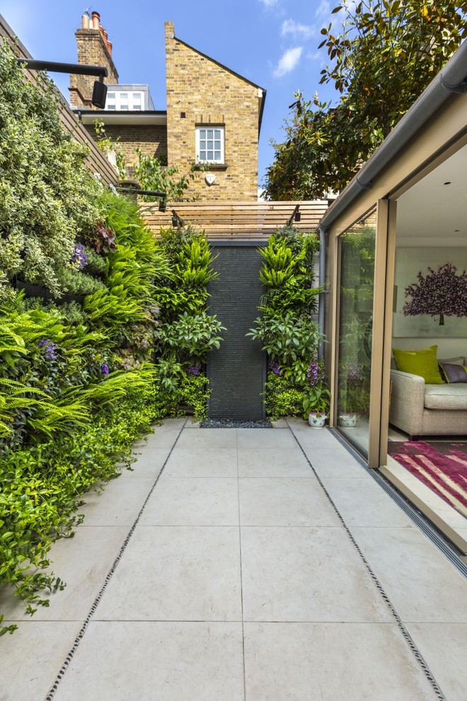 Cette photo montre un mur végétal de terrasse tendance avec des pavés en béton et aucune couverture.