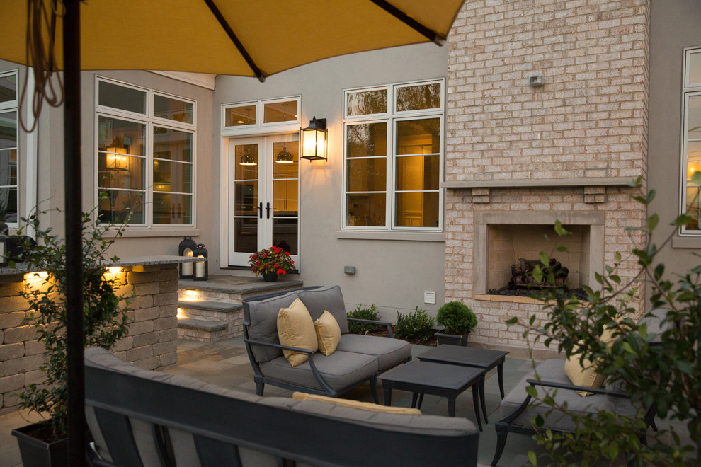 Esempio di un patio o portico tradizionale di medie dimensioni e dietro casa con un focolare, pavimentazioni in pietra naturale e un parasole