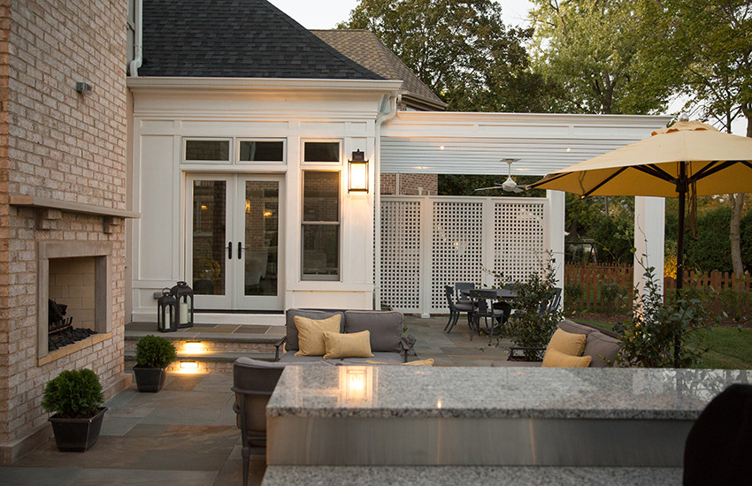 Ejemplo de patio tradicional renovado de tamaño medio en patio trasero con brasero, adoquines de piedra natural y toldo