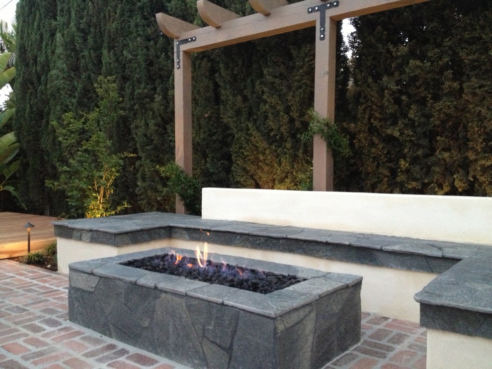 Medium sized mediterranean back patio in San Diego with a fire feature, brick paving and a pergola.
