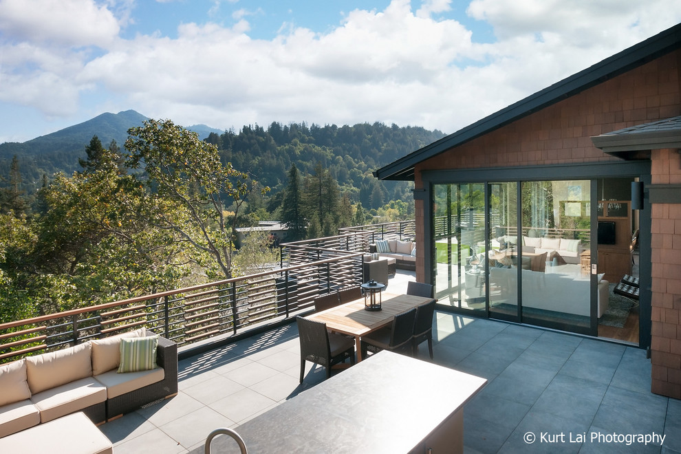 Exemple d'une grande terrasse latérale moderne avec une cuisine d'été, des pavés en pierre naturelle et aucune couverture.