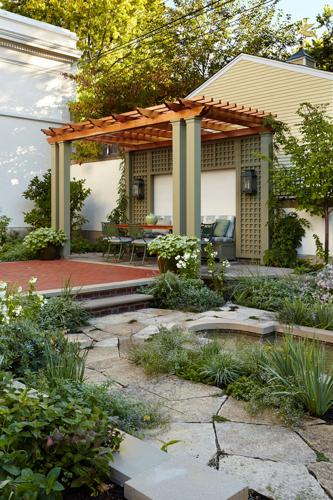 Modelo de patio clásico en patio trasero con adoquines de piedra natural y pérgola