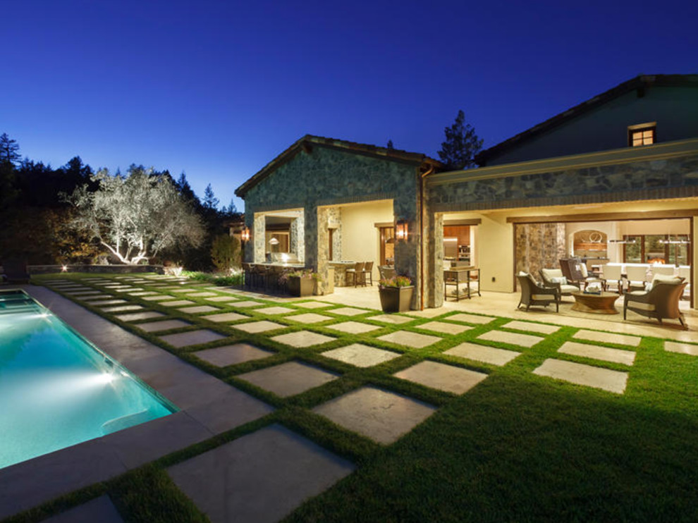 Cette image montre une terrasse design de taille moyenne avec un foyer extérieur, une cour, des pavés en pierre naturelle et une extension de toiture.