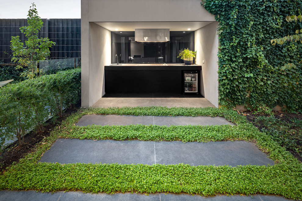 Cette photo montre une terrasse tendance avec une cuisine d'été, des pavés en pierre naturelle et une extension de toiture.