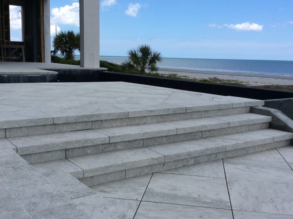 Réalisation d'une grande terrasse arrière marine avec des pavés en béton et aucune couverture.