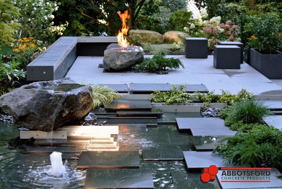 Imagen de patio minimalista grande en patio trasero con fuente y suelo de baldosas