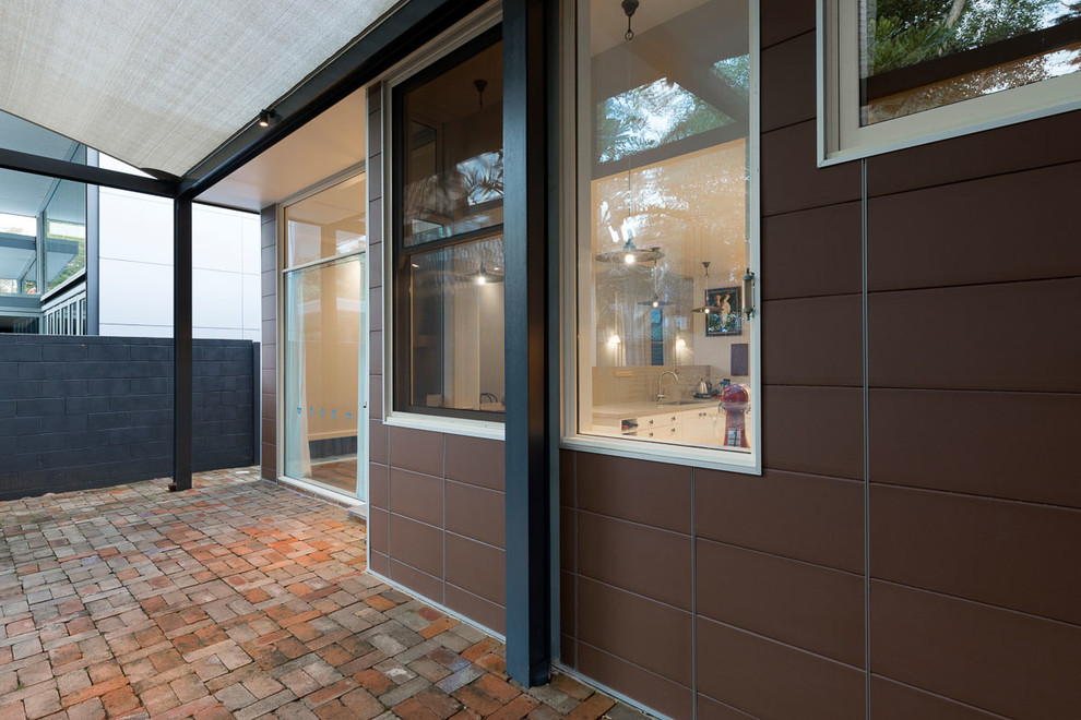 Example of a mid-sized trendy backyard brick patio design in Sydney with an awning
