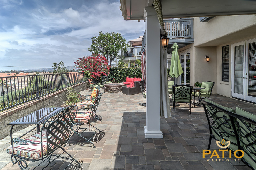This is an example of a large modern back patio in Orange County with an outdoor kitchen, concrete paving and an awning.