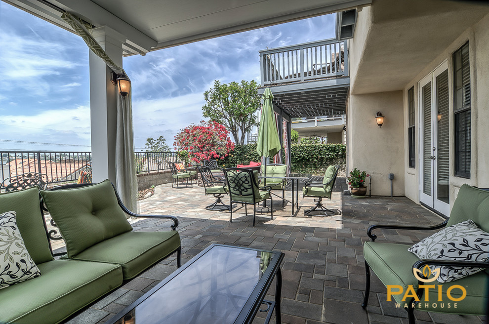 Foto di un grande patio o portico minimalista dietro casa con pavimentazioni in cemento e un parasole