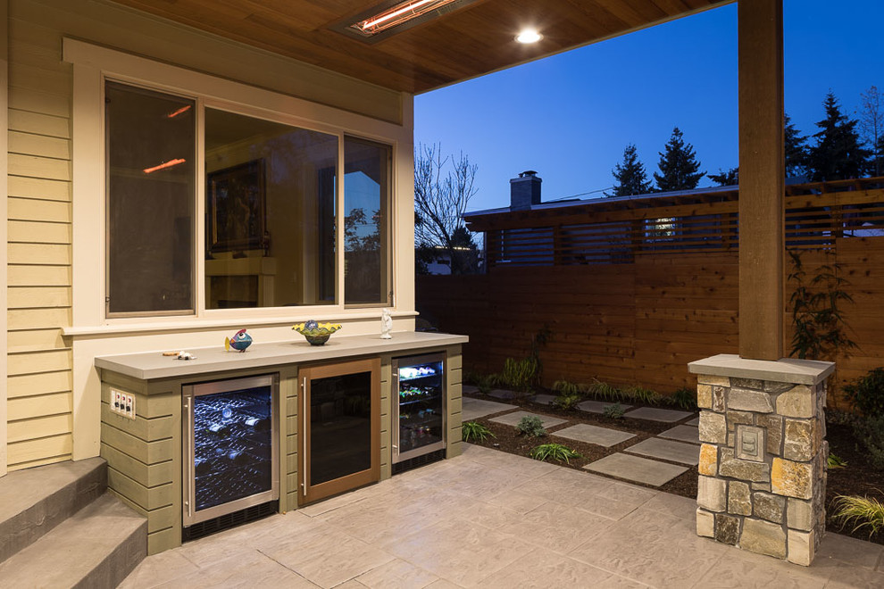 Cette photo montre une terrasse arrière chic de taille moyenne avec une cuisine d'été, une dalle de béton et une extension de toiture.