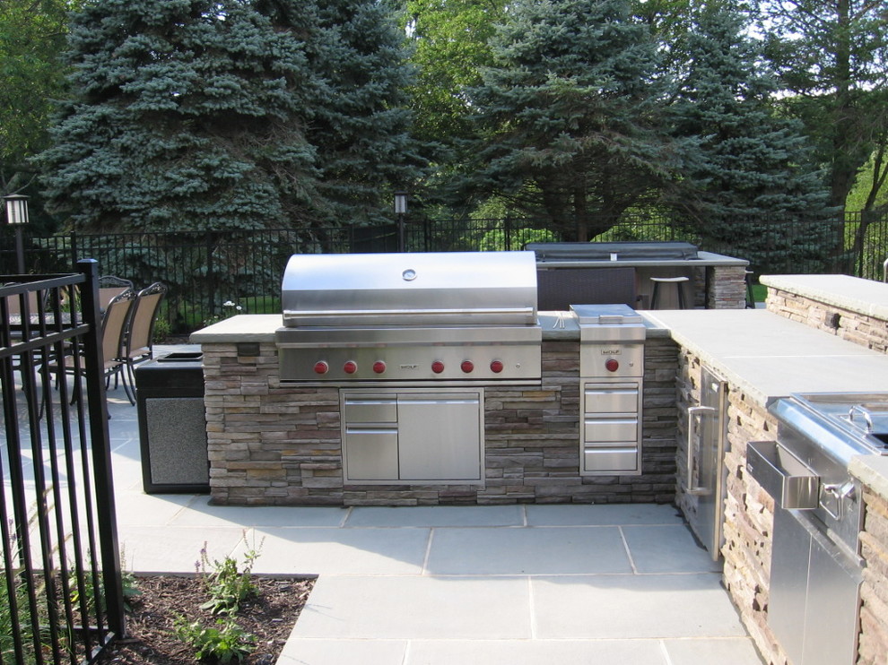 Example of a classic backyard stone patio kitchen design in New York with a gazebo