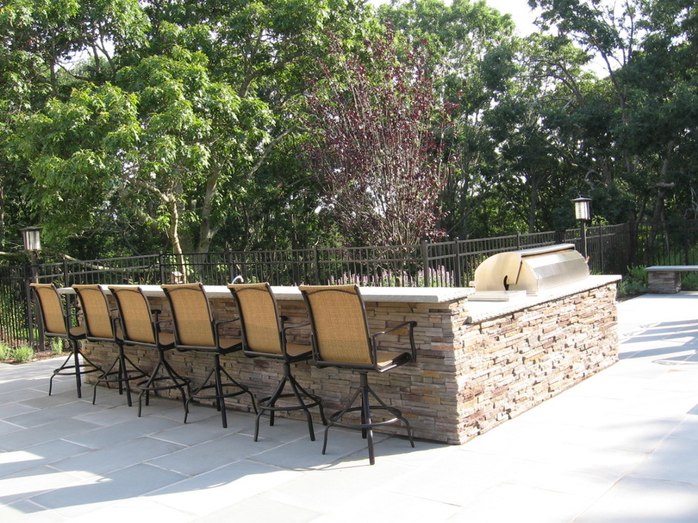 Exemple d'une terrasse arrière chic avec une cuisine d'été, des pavés en pierre naturelle et un gazebo ou pavillon.
