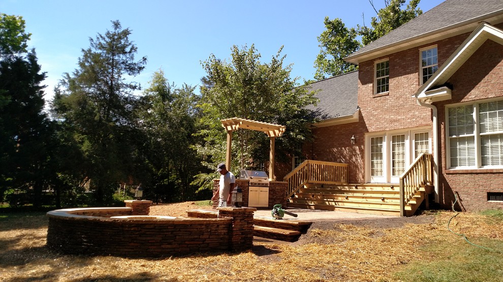 Exempel på en mellanstor rustik uteplats på baksidan av huset, med en öppen spis och naturstensplattor