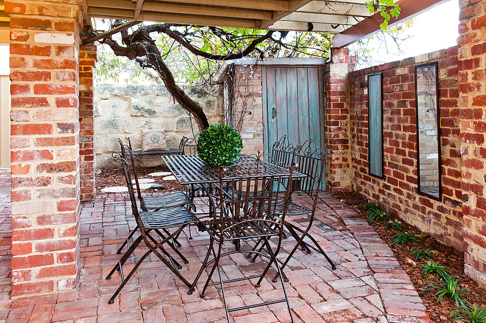 Foto de patio rústico con adoquines de ladrillo y pérgola
