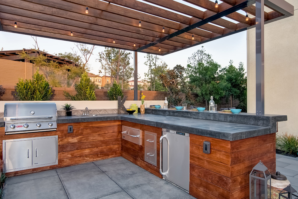 Aménagement d'une grande terrasse arrière moderne avec une cuisine d'été, des pavés en béton et une pergola.