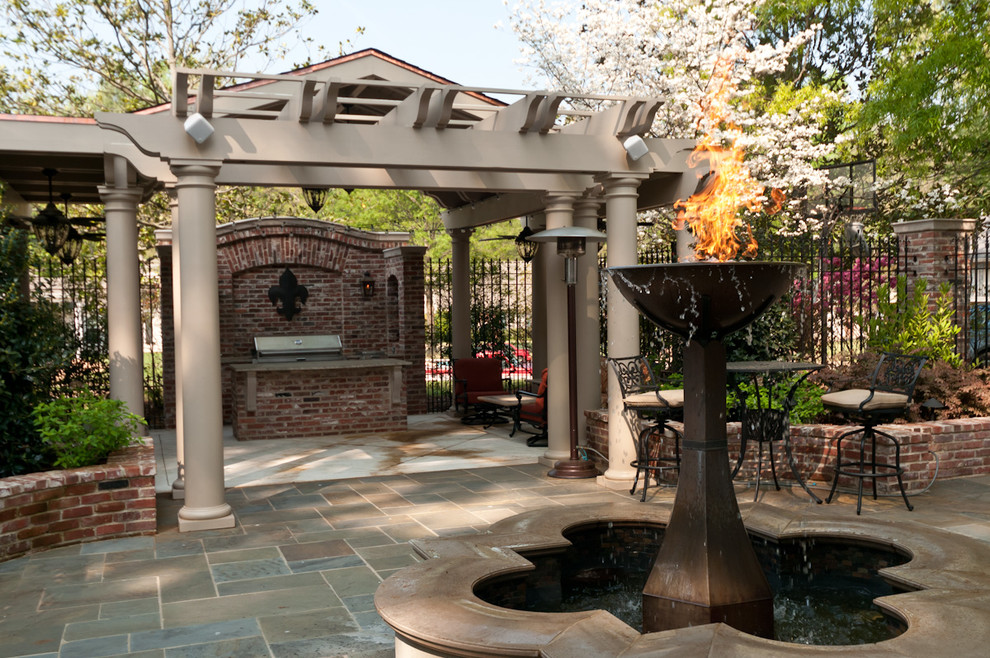 Large courtyard patio in Other with a fire feature, natural stone paving and a pergola.
