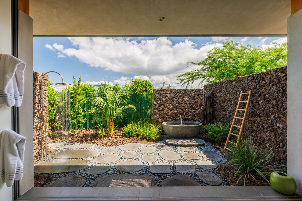 Imagen de patio tropical de tamaño medio sin cubierta en patio trasero con adoquines de piedra natural y ducha exterior