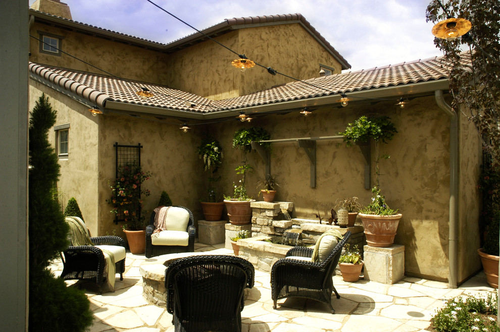Design ideas for a mediterranean courtyard patio in Denver with a water feature and natural stone paving.