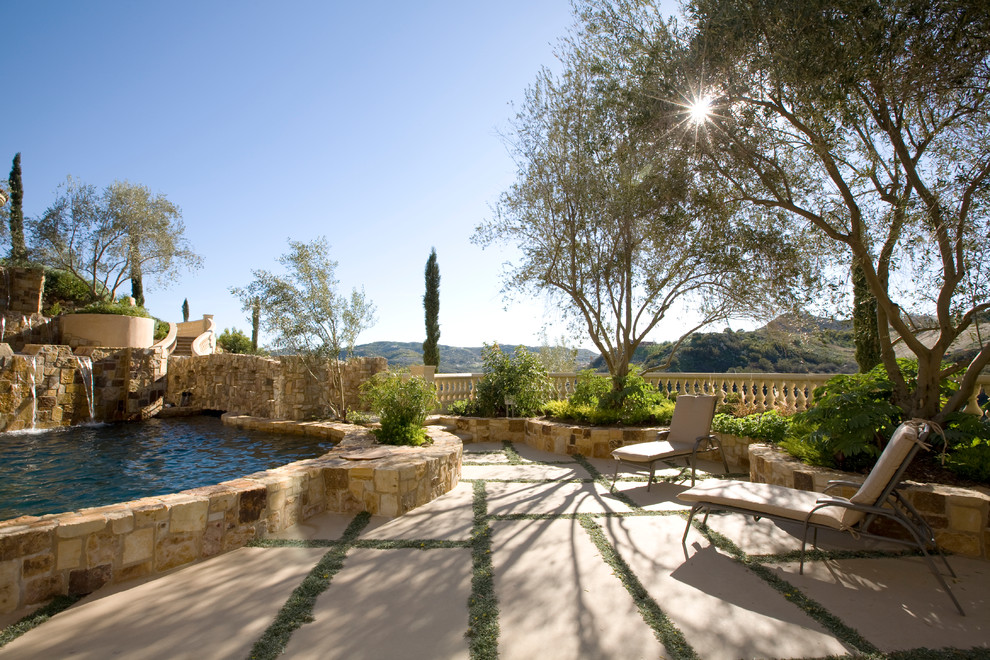 Diseño de patio mediterráneo grande sin cubierta en patio trasero con fuente y adoquines de hormigón