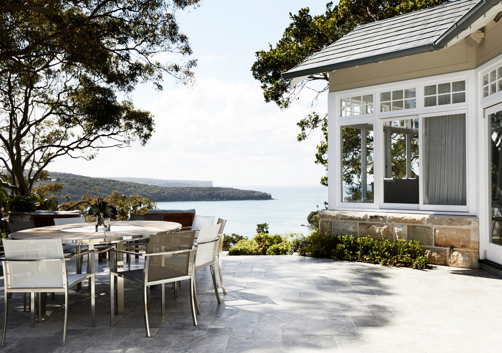Cette photo montre une grande terrasse latérale éclectique avec une cuisine d'été, des pavés en pierre naturelle et aucune couverture.
