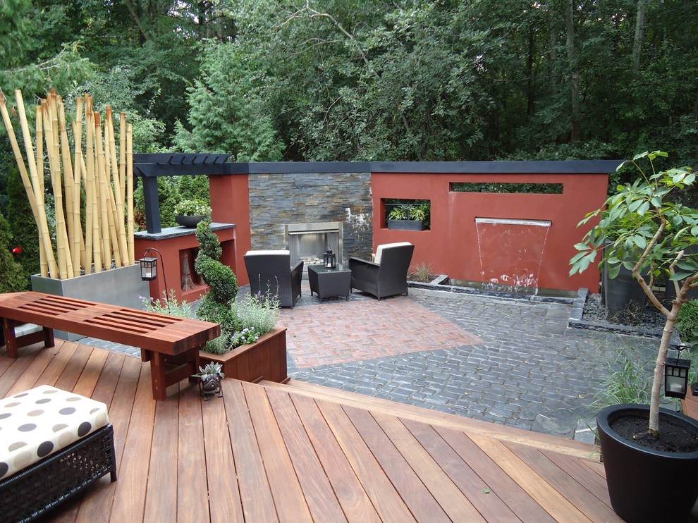 This is an example of a large contemporary back patio in Toronto with a water feature, natural stone paving and no cover.