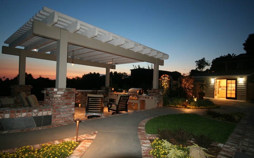 Cette photo montre une terrasse arrière éclectique de taille moyenne avec une cuisine d'été, des pavés en brique et une pergola.