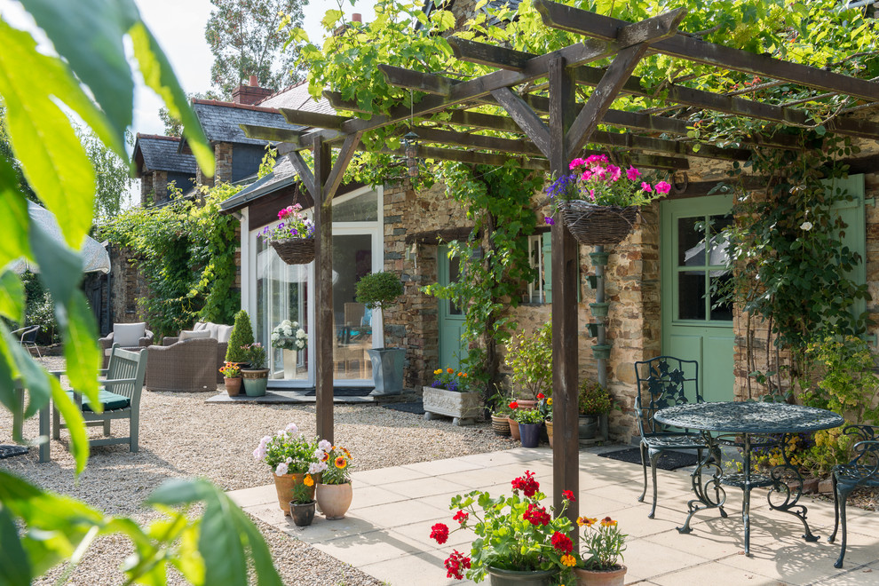 Foto di un patio o portico country di medie dimensioni e dietro casa con un giardino in vaso, lastre di cemento e una pergola