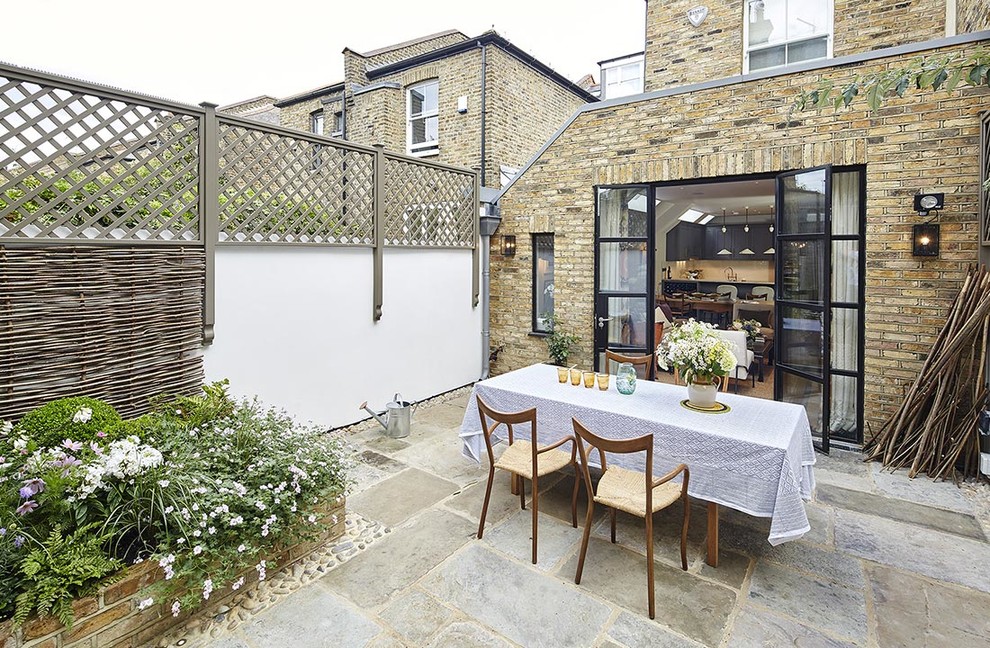 Design ideas for a medium sized traditional back patio in London with natural stone paving.