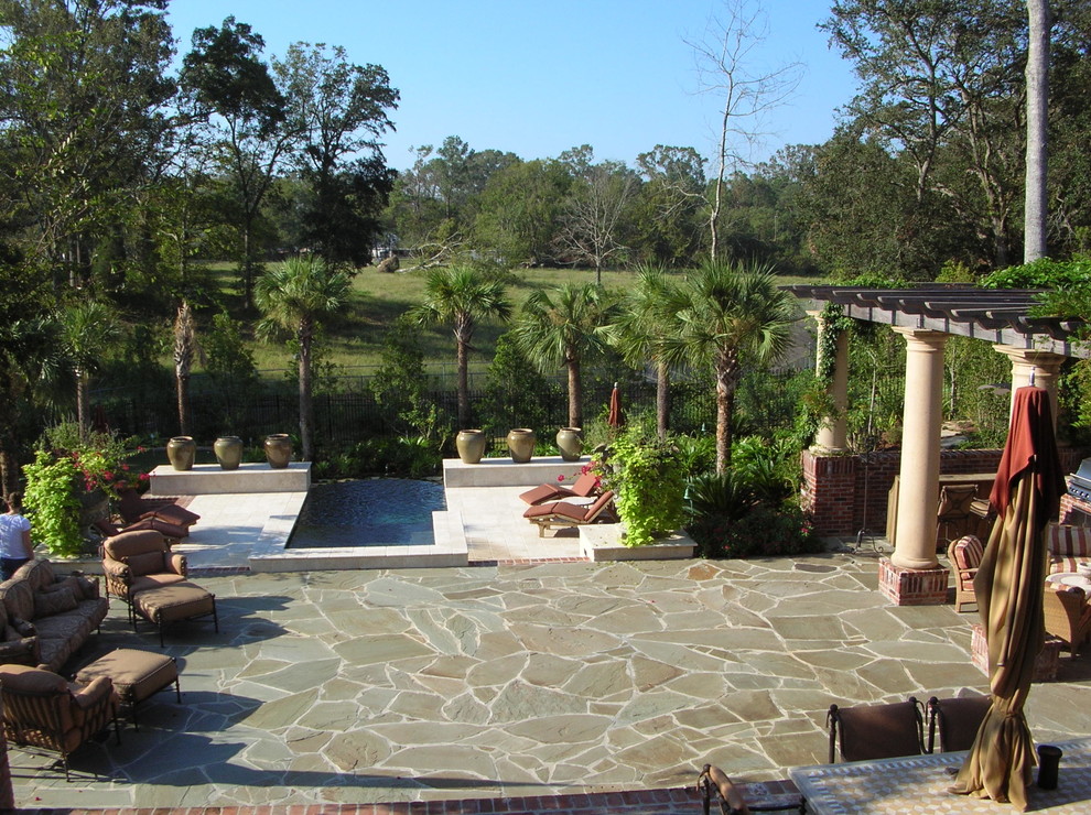 Immagine di un grande patio o portico tropicale dietro casa con fontane, pavimentazioni in pietra naturale e una pergola