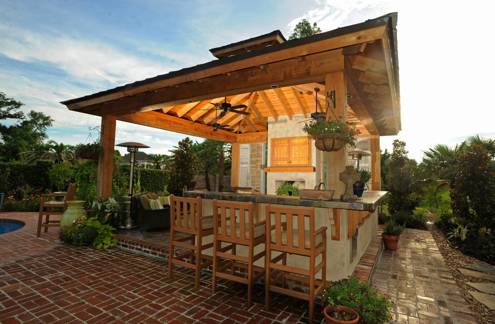 Idee per un patio o portico tradizionale di medie dimensioni e dietro casa con pavimentazioni in mattoni e un tetto a sbalzo
