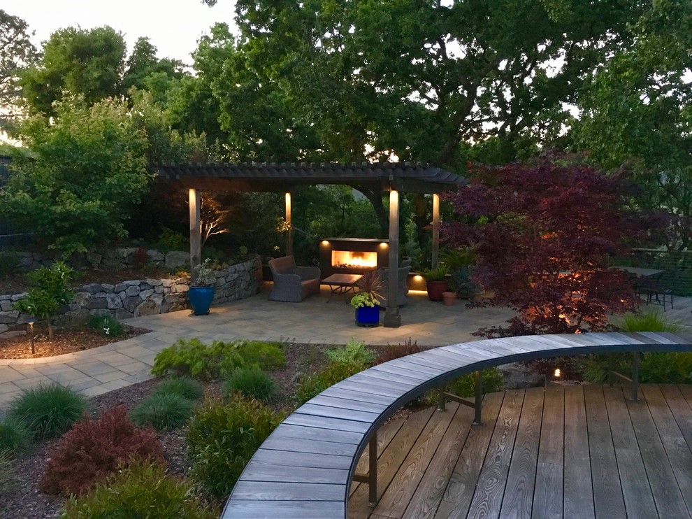 Cette image montre une terrasse en bois arrière design de taille moyenne avec un foyer extérieur et une pergola.
